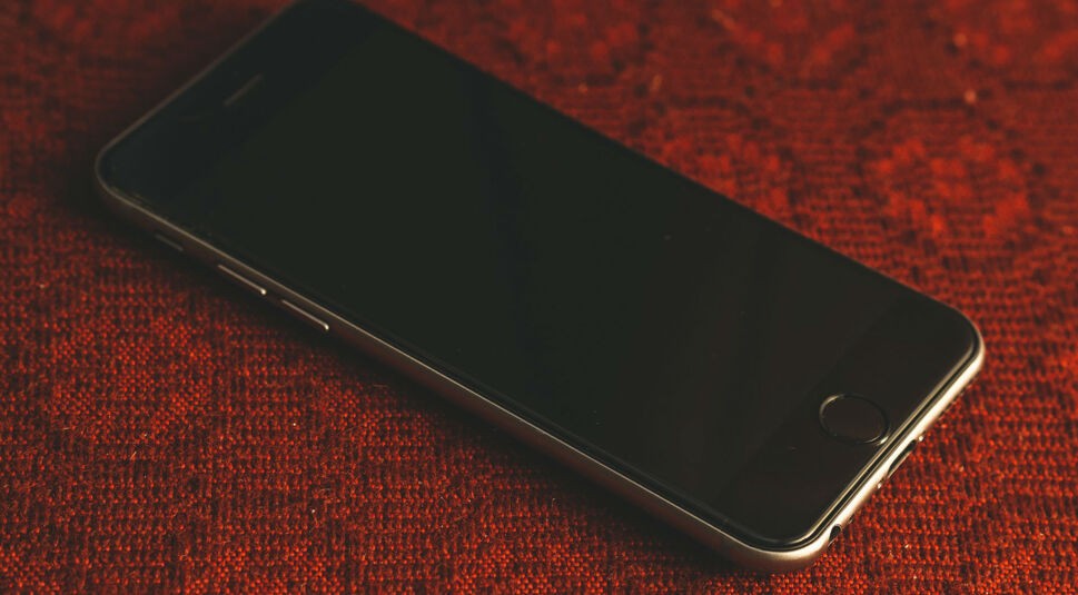 Schwarzes iPhone liegt auf rotem Teppichboden