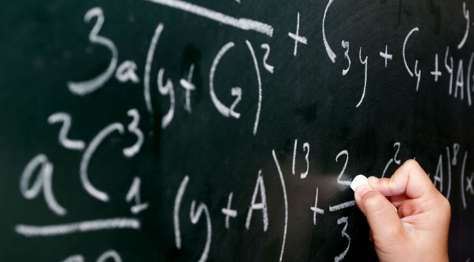 Hand schreibt mathematische Formeln auf eine Tafel.