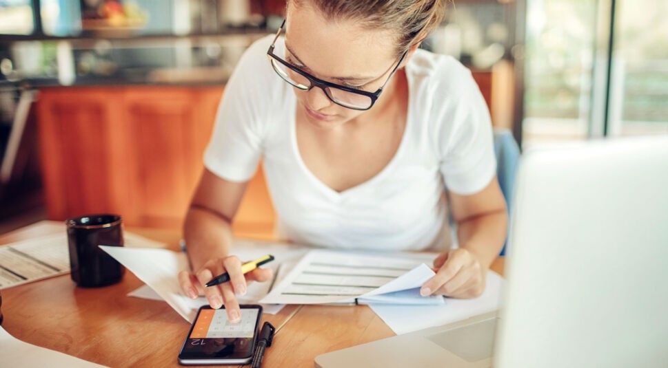 Junge Frau rechnet mit dem Taschenrechner.