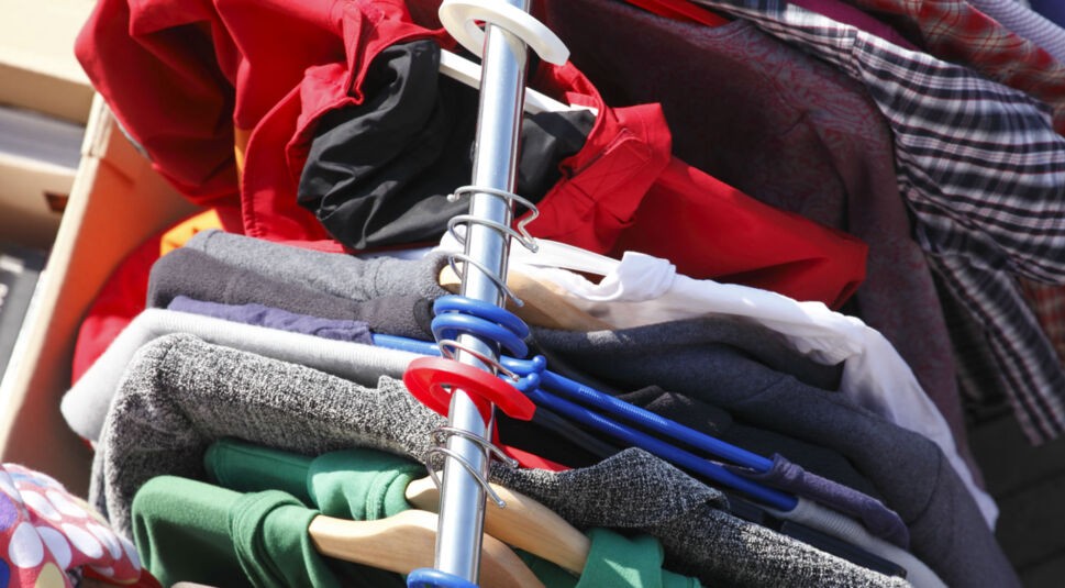 Stange an Kleidern auf dem Flohmarkt.