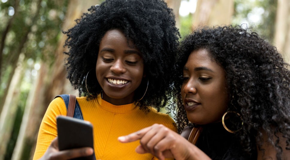 Zwei junge Frauen chatten übers Smartphone.