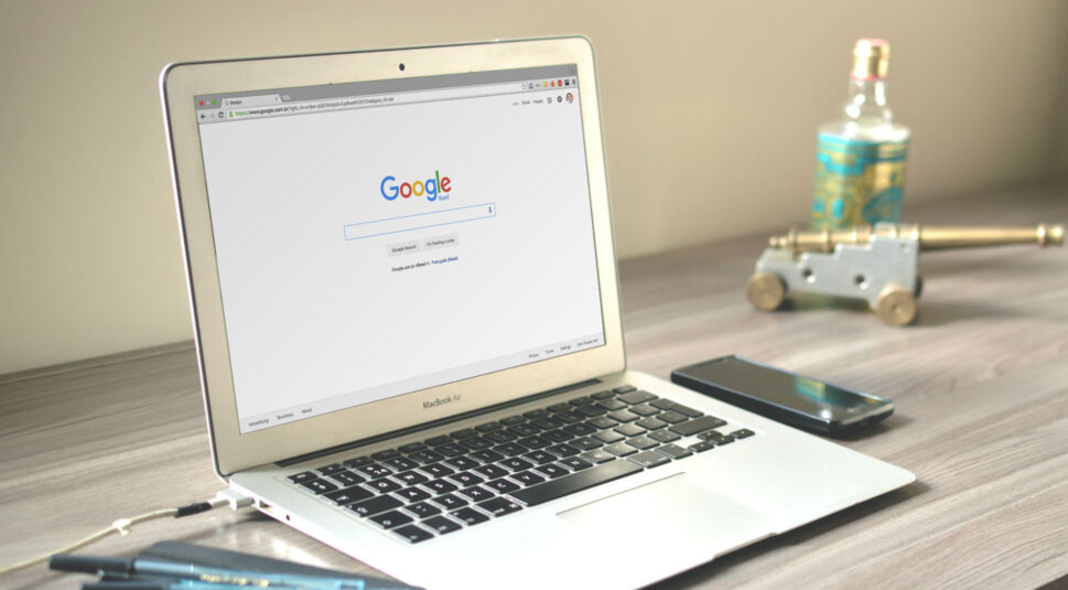 Weißes Macbook Air liegt auf einem Schreibtisch.