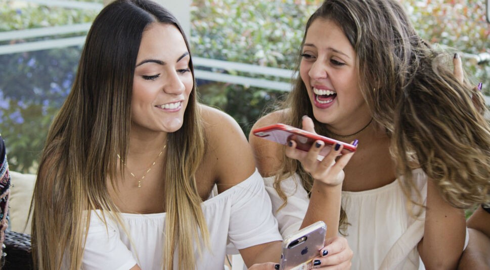 Zwei Freundinnen chatten über ihre iPhones.