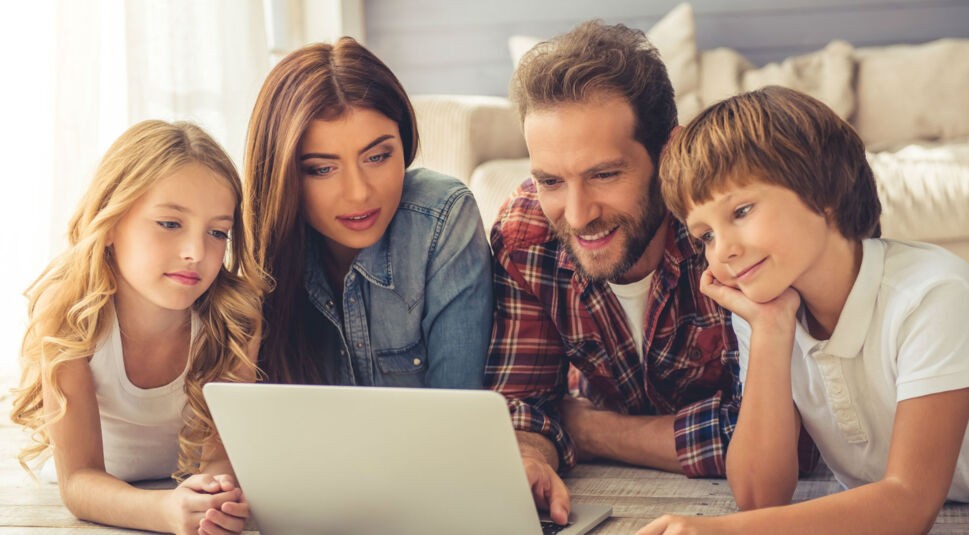 Junge Familie hört Musik über einen Laptop.