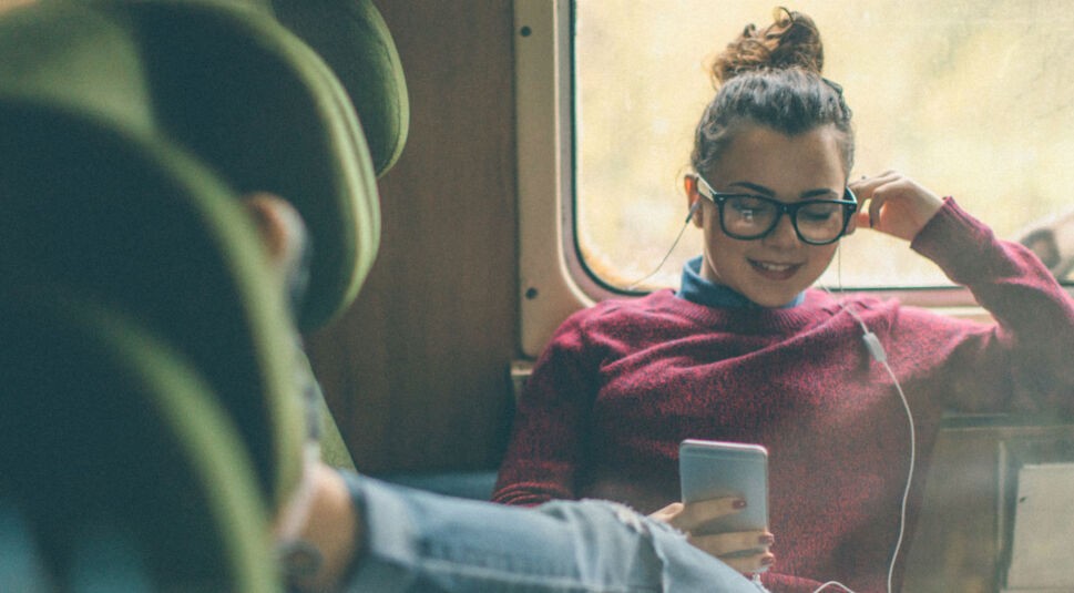 Junge Frau hört Musik, während sie im Zug sitzt.