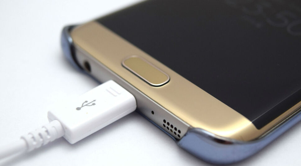 Goldenes Smartphones wird per Kabel aufgeladen.
