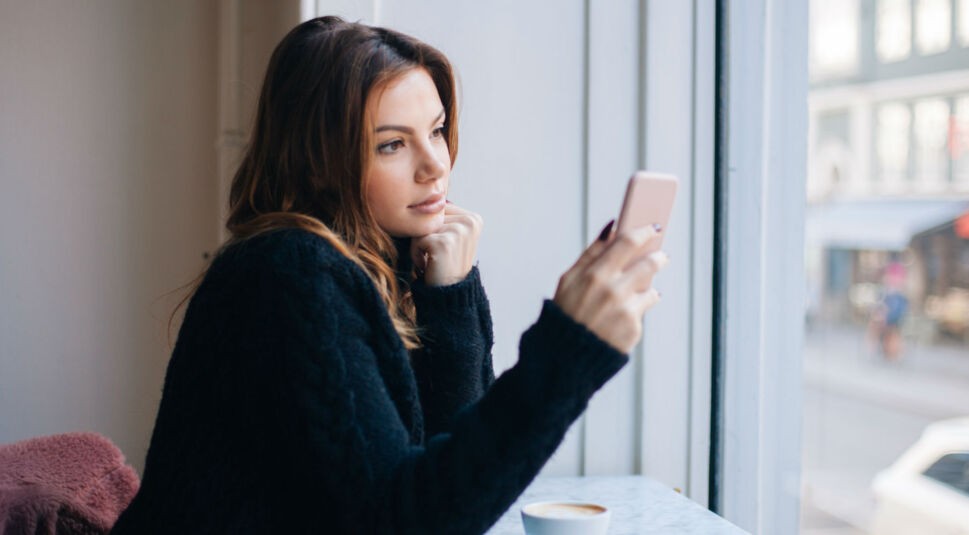 Junge Frau ändert die Einstellungen von Instagram auf ihrem Smartphone.