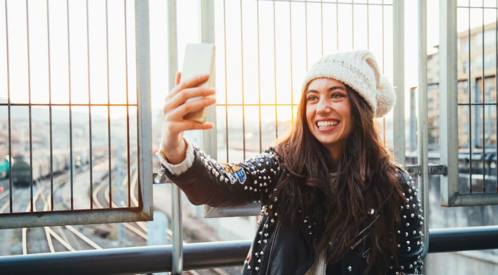 Junge Frau schießt ein Selfie mit ihrem Smartphone.