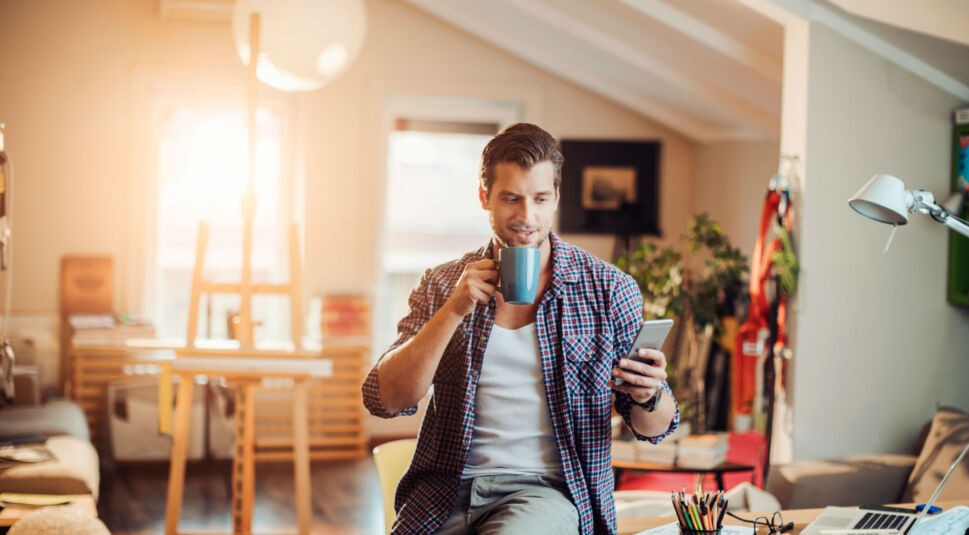 Mann steuert sein smartes Zuhause über sein Smartphone.