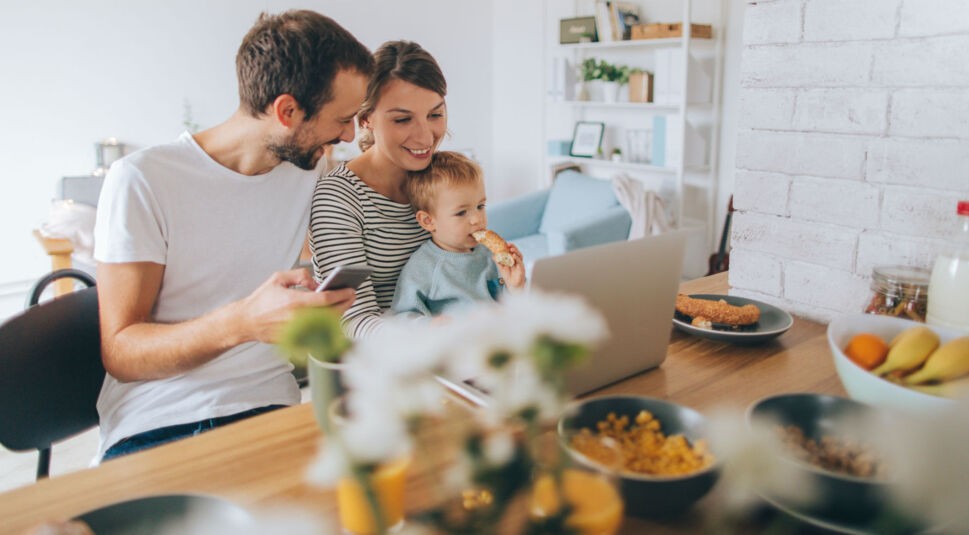 Junge Familie sitzt vor dem Laptop.