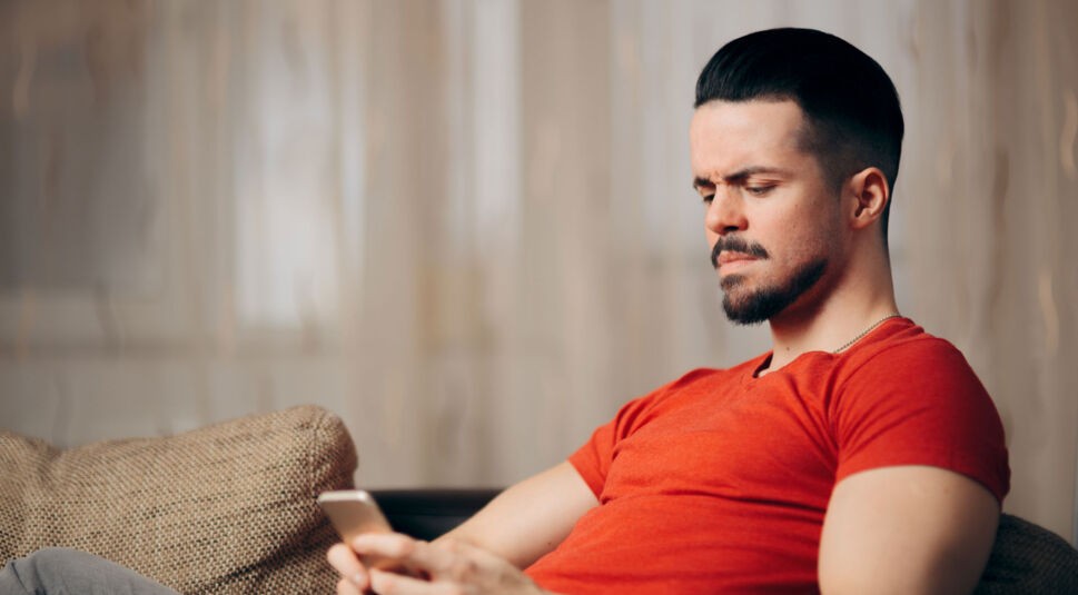 Ein Mann schaut skeptisch auf sein Smartphone.
