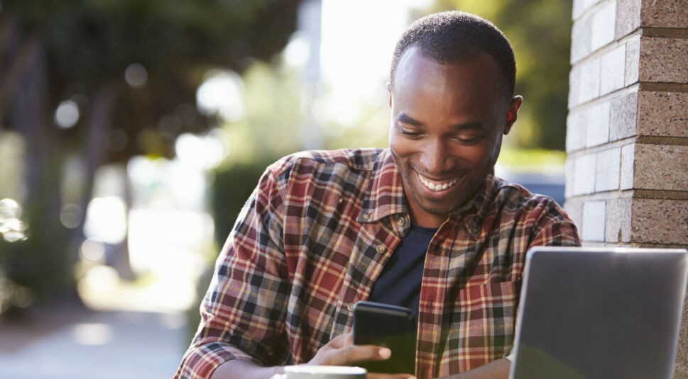 Junger Mann sucht Apps über den Google Play Store am Smartphone.