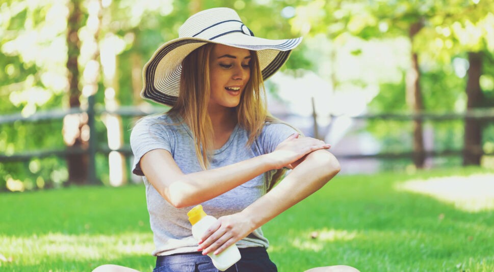 Junge Frau trägt Sonnencreme auf ihre Haut auf.