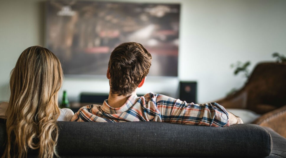 Zwei Menschen sitzen vor dem Fernseher.