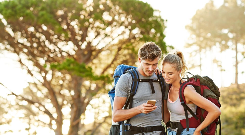 Ein Paar prüft während einer Wanderung etwas auf dem Smartphone.