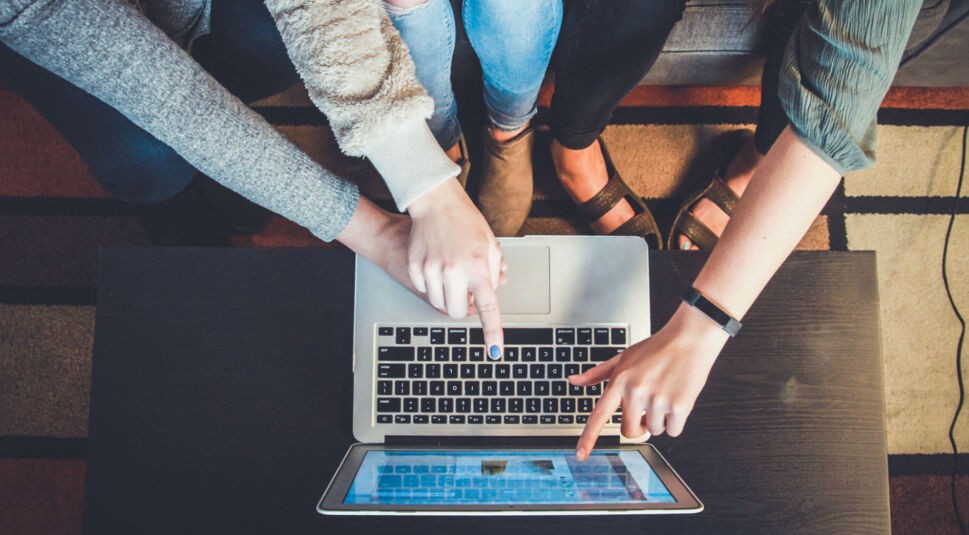 Freundinnen nutzen ein Macbook.