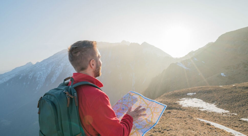 Junger Mann plant mit Landkarte seine Route.