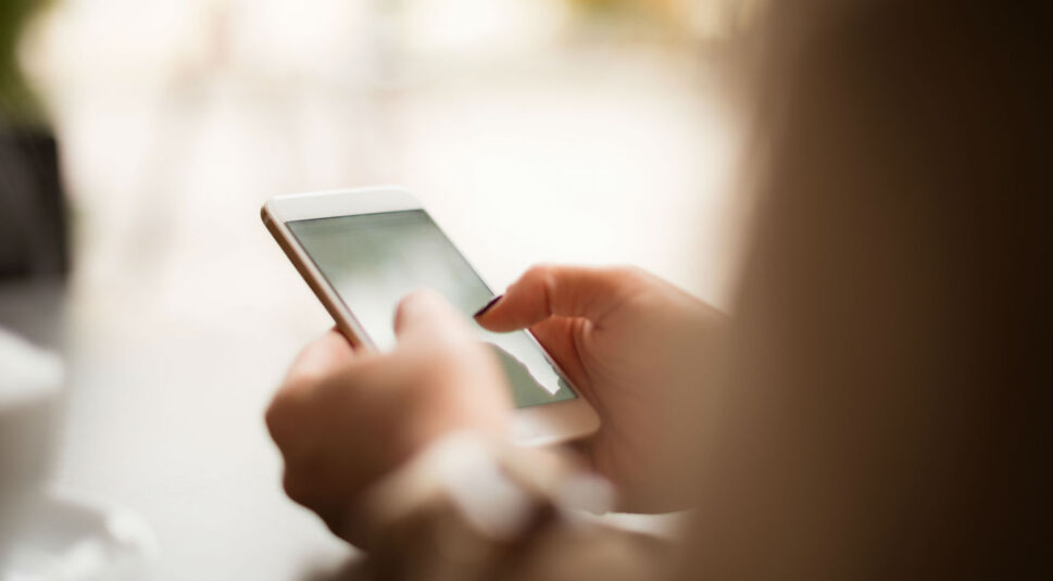 Junge Frau stöbert am Smartphone durch den neuen Google-Feed.