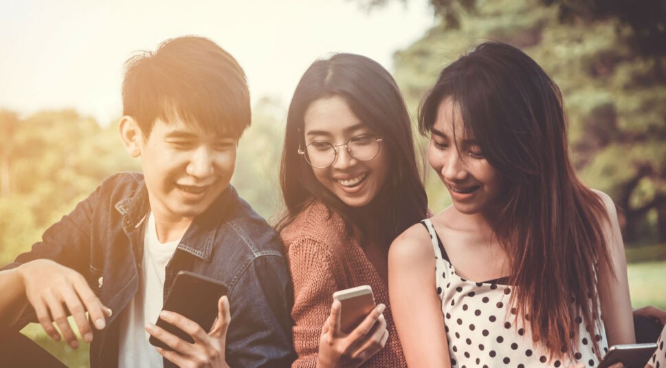 Freunde sitzen zusammen und chatten über ihre Smartphones.