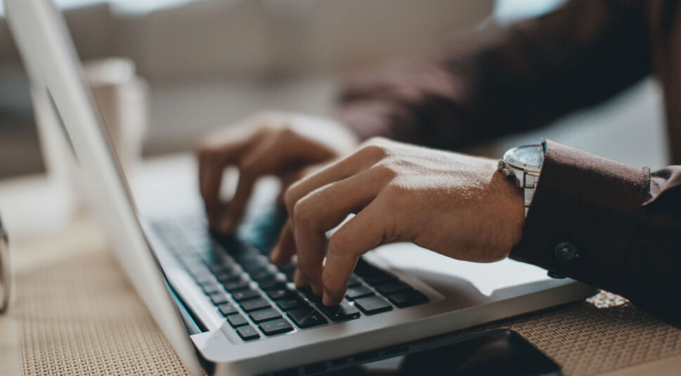 Junger Mann tippt auf seinem Laptop.