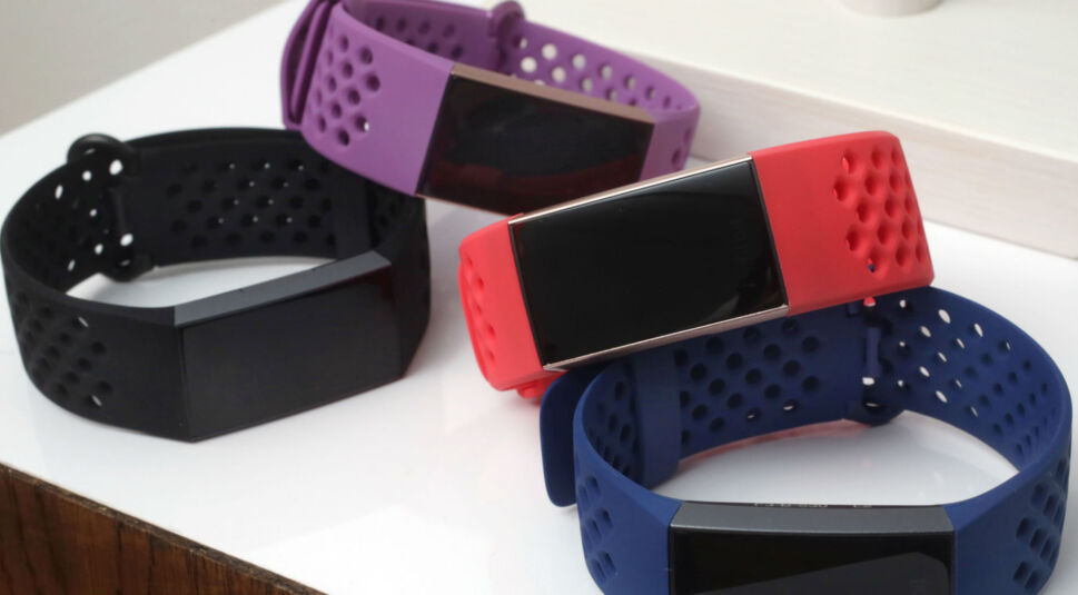 Mehrere Fitbit Charge 3 liegen gestapelt auf einem Tisch.