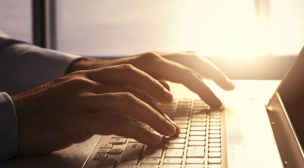 Mann tippt auf der Tastatur seine MacBooks.