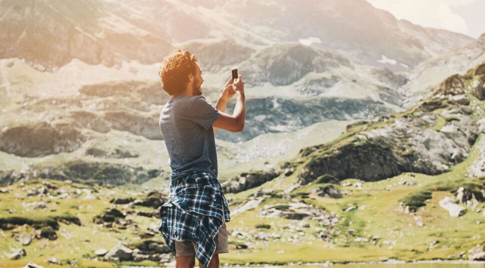 Junger Mann nimmt mit dem Smartphone ein Foto auf.