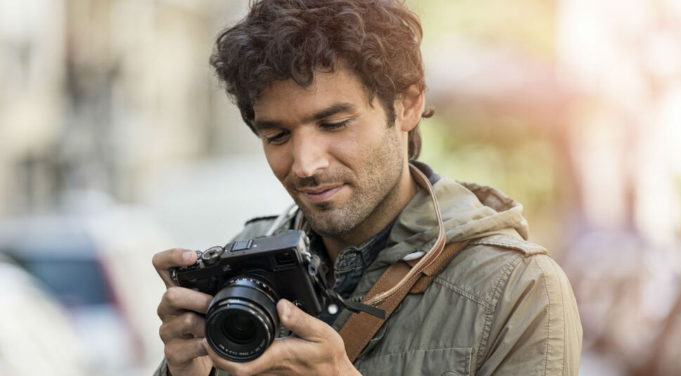 Junger Mann stellt seine Kamera ein.