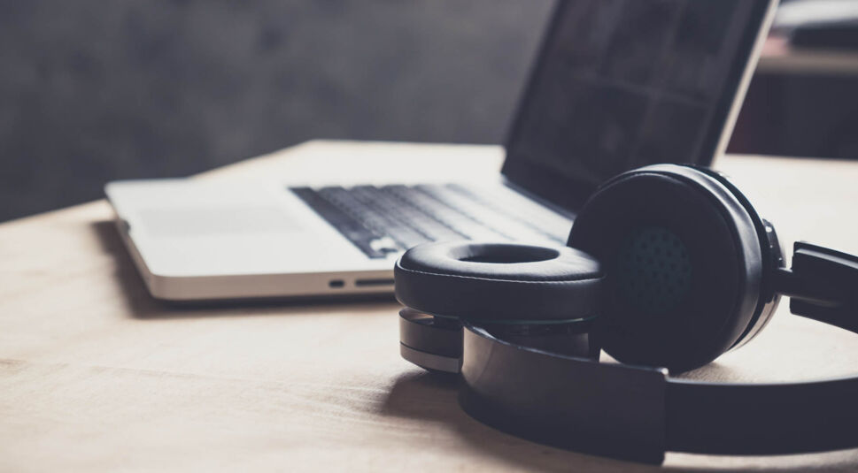 Bluetooth-Kopfhörer liegen neben einem Macbook.