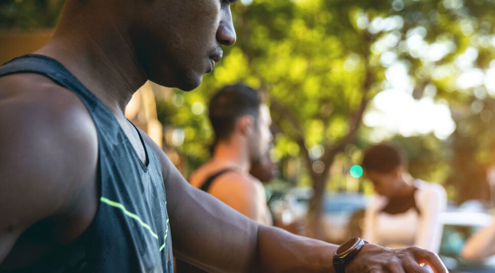 Junger Mann schaut auf seine Smartwatch.