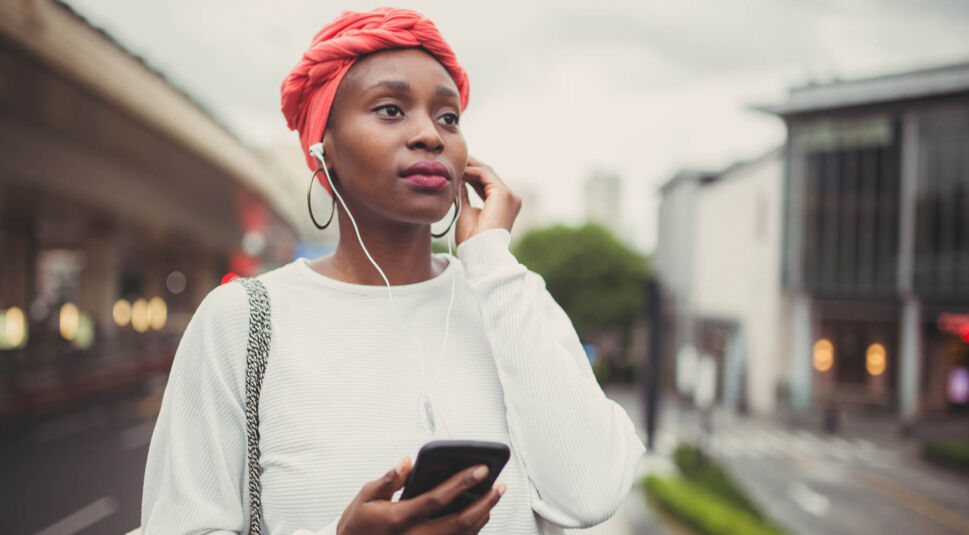 Junge Frau hört via Android-Smartphone Musik.