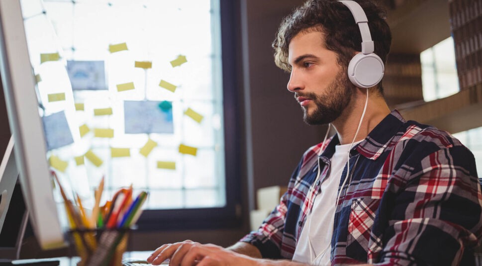 Junger Mann aktiviert den iTunes-Miniplayer am Mac, indem er drei Tasten drückt.