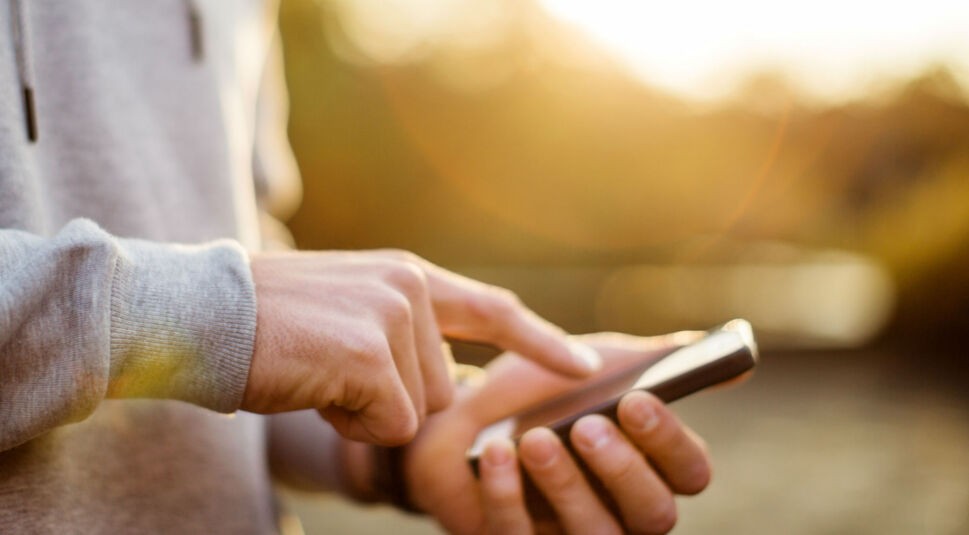 Junger Mann verknüpft am Smartphone Youtube Music mit dem Google Assistant.