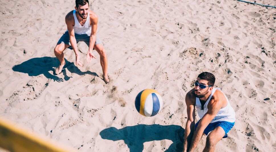 Zwei junge Männer spielen Beachvolleyball