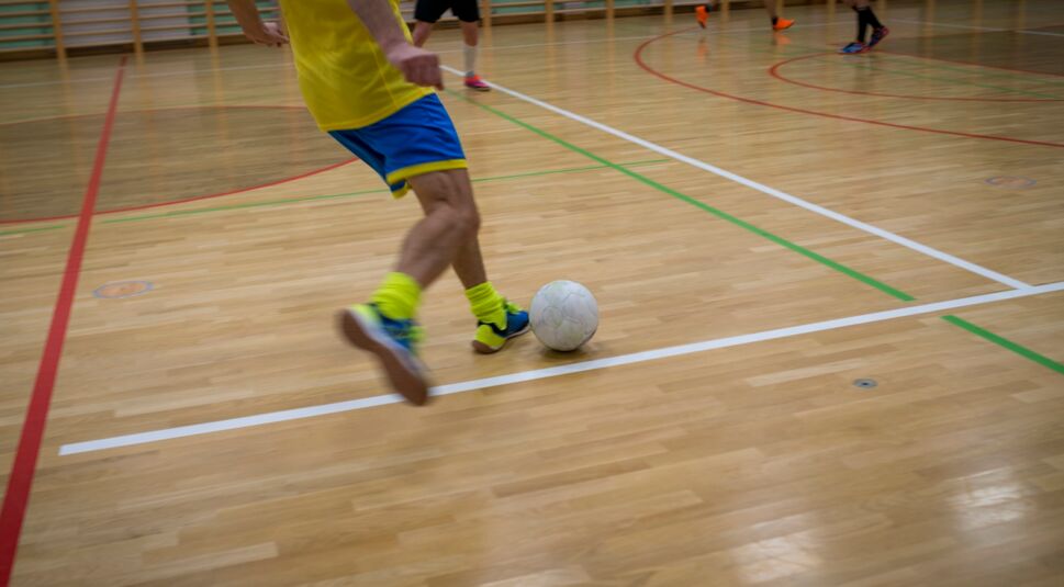 Junger Sportler spielt Fußball in der Halle