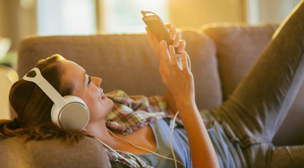 Junge Frau stellt am Smartphone ihre Deezer-Playlist ein.