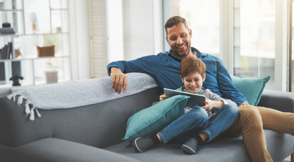 Ein Vater spielt mit seinem Sohn am Tablet.