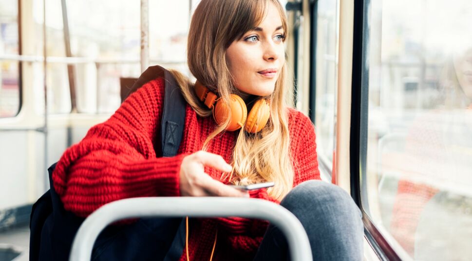 Junge Frau sitzt im Bus und hört ihre Lieblingsmusik.