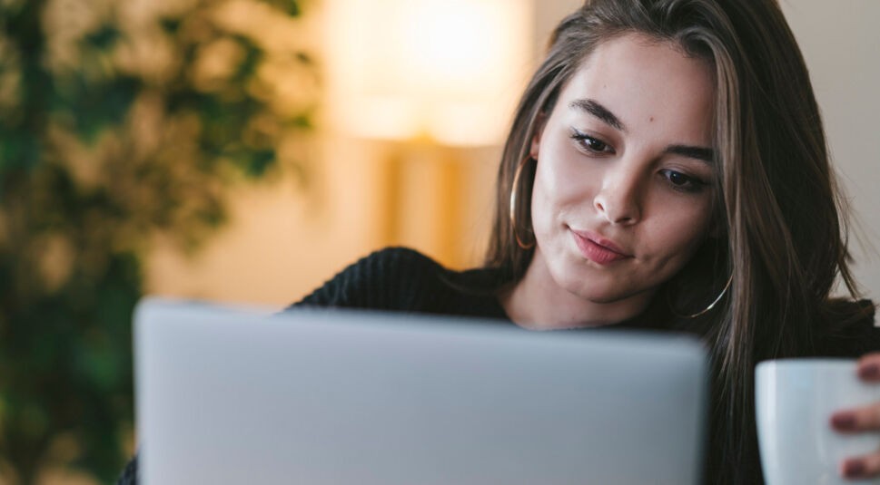 Junge Frau sucht am Laptop nach Netflix.