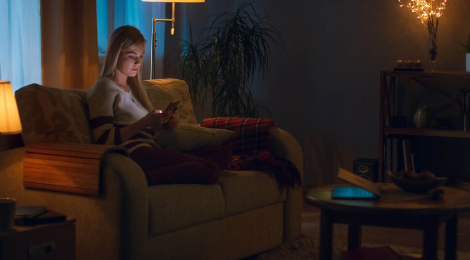 Frau sieht sich am Smartphone den Dark Mode des Google Kalenders an.