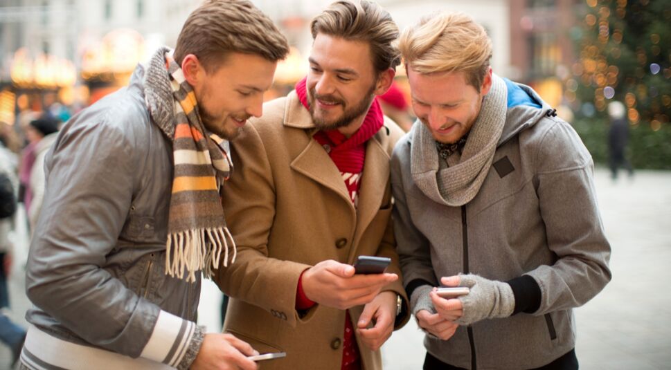 Eine Gruppe junger Männer spielt Skat via Smartphone.