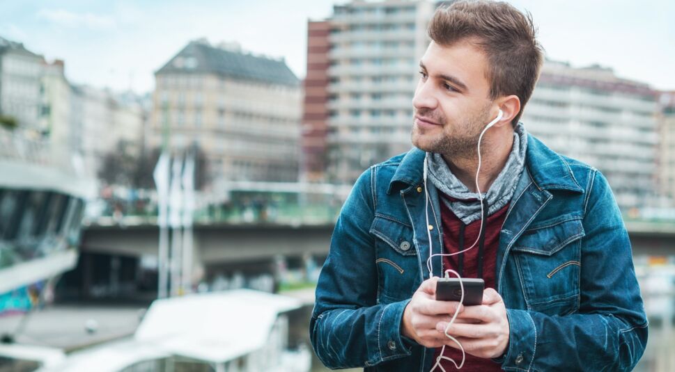 Junger Mann hört Musik über Spotify