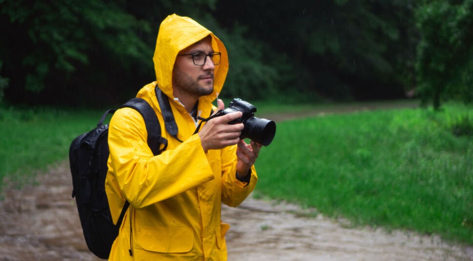 Mann fotografiert mit seiner Kamera im Regen.