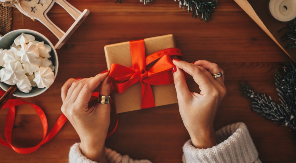 Frau verpackt Geschenk, in dem smarter Schmuck ist.