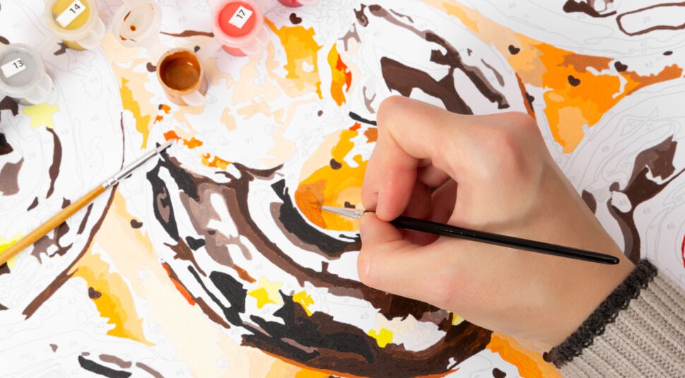 Hand mit Pinsel und Malen-nach-Zahlen-Bild