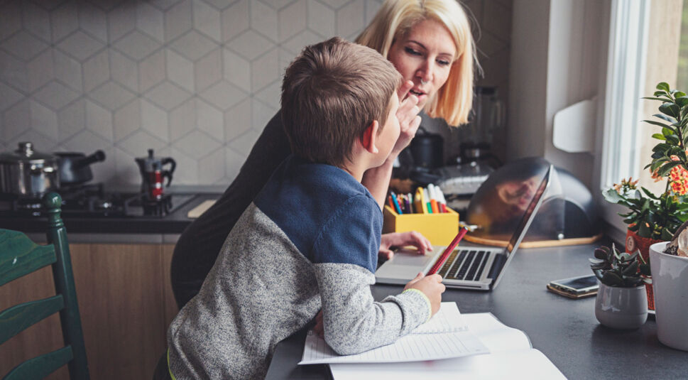 Eine Mutter lernt mit ihrem Sohn am Notebook in der Küche.