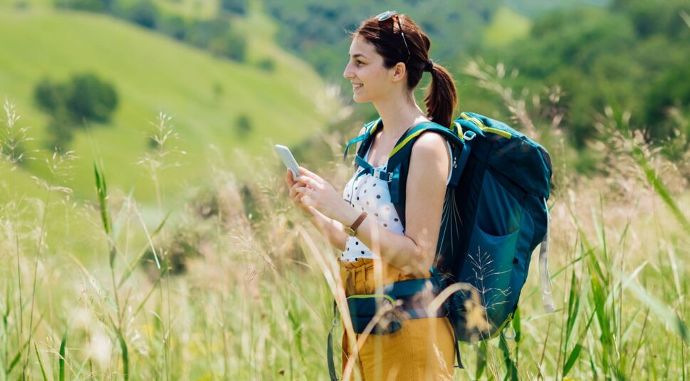 Frau wandert mit Smartphone in der Hand.