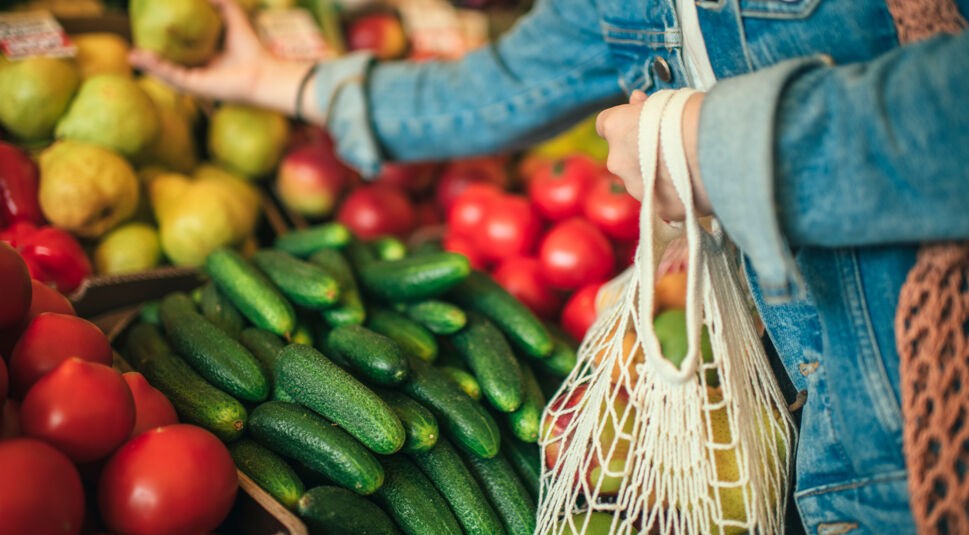 Eine Frau packt im Supermarkt Gemüse in ihr Einkaufnetz.
