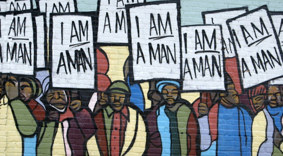 Ein Wandgraffiti zeigt schwarze Männer, die mit Schildern mit der Aufschrift "I am a man" protestieren.