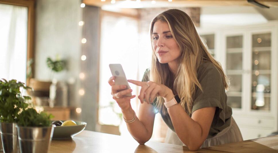 Eine Frau schaut auf ihr Smartphone, um ein Weihnachtsgeschenk zu tauschen 